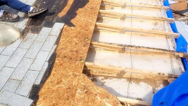 Roof opened up after storm damage, with exposed decking and rafters